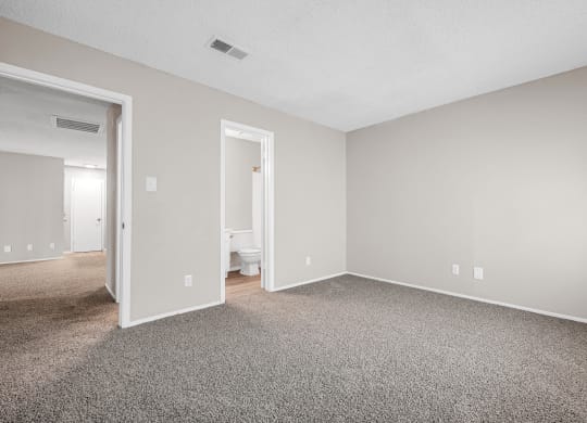 an empty living room with carpet and a door to a bathroom