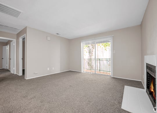 an empty living room with a fireplace and a door to a balcony