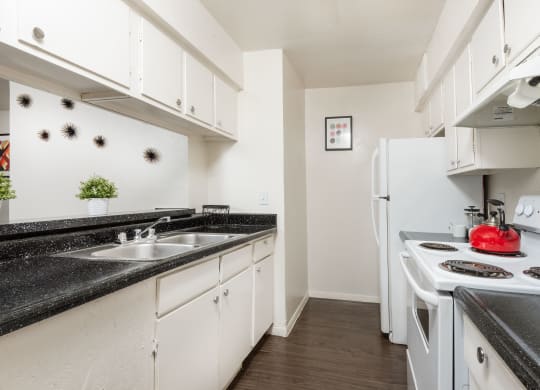 a kitchen with white appliances and black counter tops and white cabinets  at Lumina, Dallas, 75240