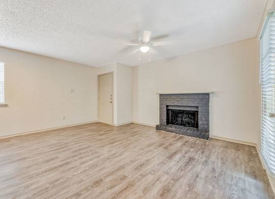 an empty living room with a fireplace and a ceiling fan