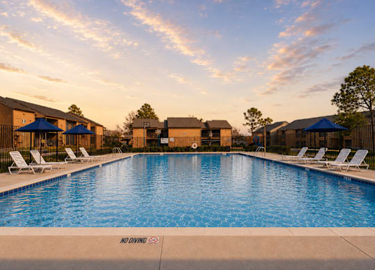 Swimming pool with lounge chairs at sunset at Ridgeview Apartments, Sherman, TX 75092