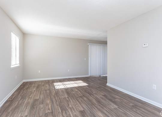 an empty living room with wood flooring and white walls at Rosen at North Hills, Raleigh
