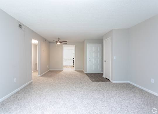 an empty living room with white carpet and a ceiling fan at Rosen at North Hills, Raleigh, NC