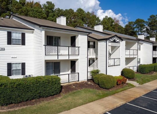 an apartment building with white siding and a sidewalk