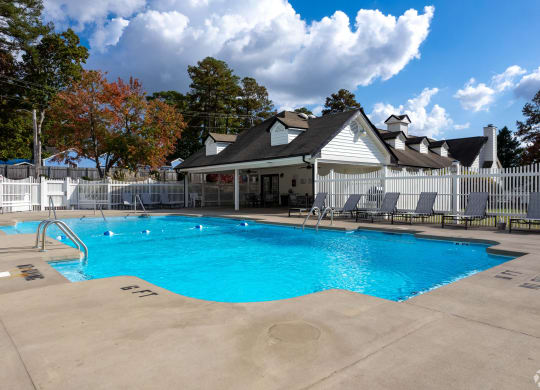 a swimming pool with chairs around it in front of a building