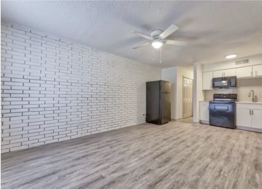 an open living room with a kitchen and a ceiling fan