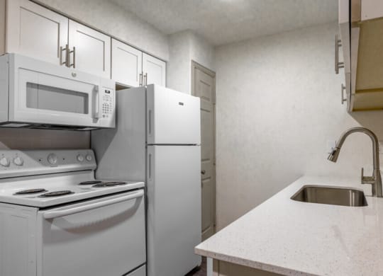 a long row of microwaves in a kitchen with white cabinets