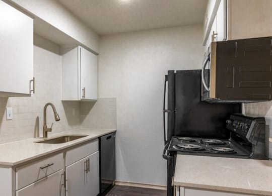 an empty kitchen with white cabinets and a black stove and refrigerator