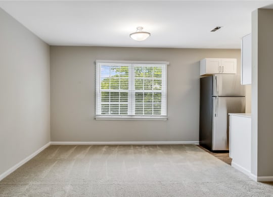 an empty kitchen with a window and a refrigerator