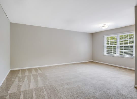 an empty room with a window and white walls