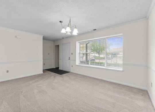 an empty living room with a large window and white walls