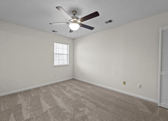 the living room is empty and has a ceiling fan