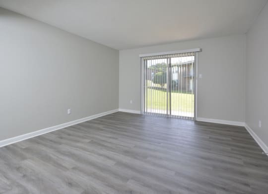 an empty living room with a sliding glass door to a yard