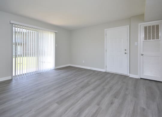 an empty living room with wood floors and a white door