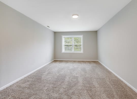 an empty room with carpet and a window