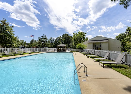 A large swimming pool surrounded by trees and a building in the background.