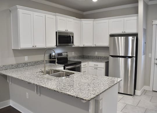 A kitchen with granite countertops and stainless steel appliances at Cedar Crest Apartments, Arkansas, 72730