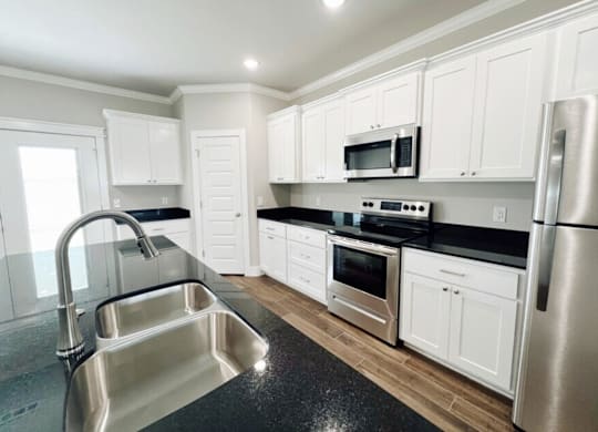A kitchen with white cabinets and stainless steel appliances at Cedar Crest Apartments, Arkansas