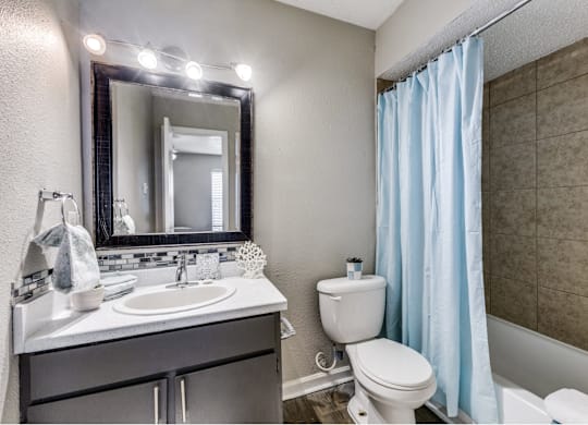 A bathroom with a white toilet, sink, and a mirror with lights.