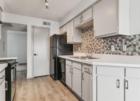 a kitchen with white cabinets and a black refrigerator