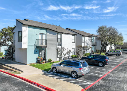 an apartment building with a parking lot and cars in front of it