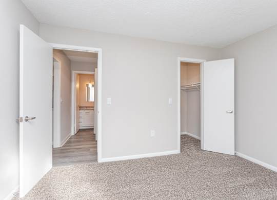 an empty bedroom with a hallway to the bathroom and a closet