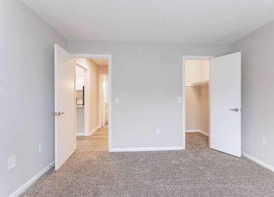 an empty room with two doors and a carpeted floor