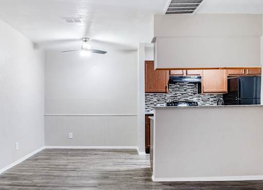 Open living area with ceiling fan and kitchen view at Ridgeview Apartments, Sherman, TX