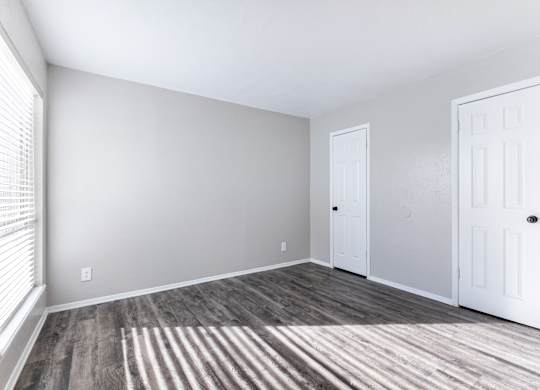 Empty bedroom with white doors and window blinds at Ridgeview Apartments, Texas, 75092
