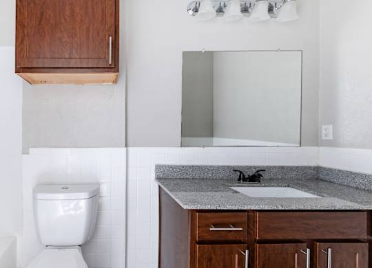 Bathroom vanity with granite countertop and mirrored medicine cabinet at Ridgeview Apartments, Sherman, TX