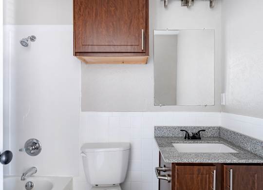 Bathroom with wood cabinetry and granite vanity at Ridgeview Apartments, Texas, 75092
