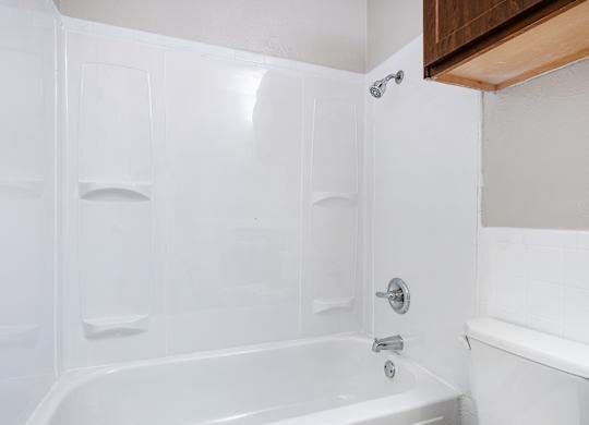 White tub shower surround with chrome fixtures at Ridgeview Apartments, Sherman, TX 75092