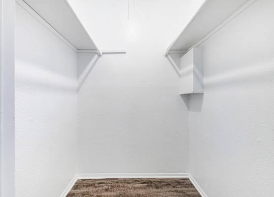 Walk-in closet with hanging rods and corner shelf at Ridgeview Apartments, Sherman, TX