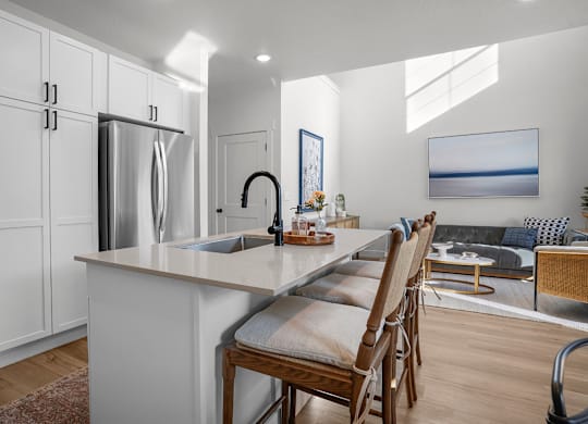 A kitchen with a refrigerator, sink, and a dining table with chairs.