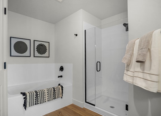 A white bathroom with a towel hanging on the door.