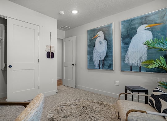 A room with a painting of a white bird on the wall.