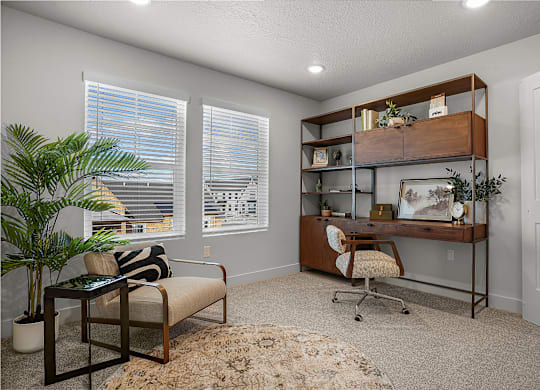 A room with a couch, chair, and desk with a shelf above it.