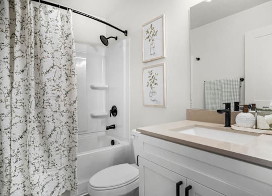 A white bathroom with a toilet, sink, and shower.