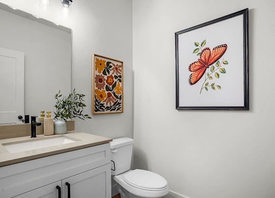 A bathroom with a toilet, sink, and a picture of a butterfly on the wall.