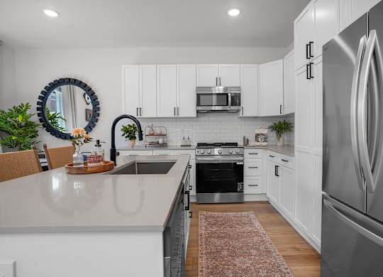 A modern kitchen with white cabinets and stainless steel appliances.