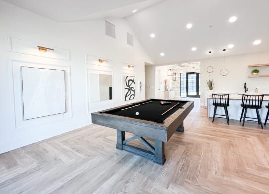 a billiards table in a game room with a dining area and a kitchen