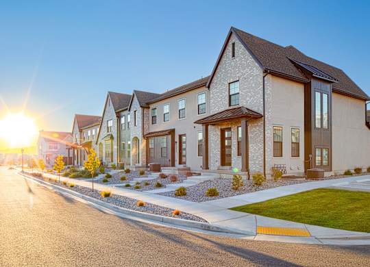 A row of houses with a sunset in the background.