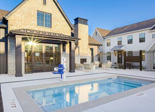 A pool in a backyard with a blue chair and a white bench.