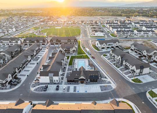 A sunset view of a residential area with houses and a pool.