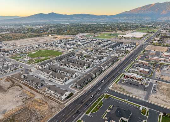 A large, modern housing development is under construction in a valley with mountains in the background.