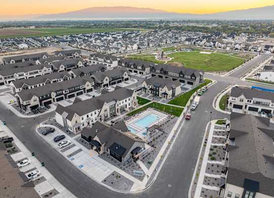 A sunset view of a residential area with houses and a pool.