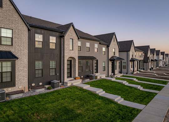 A row of houses with a green lawn in front.