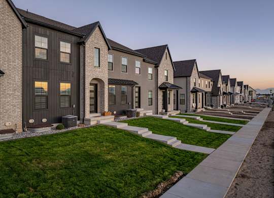 A row of new houses with dark grey exteriors and white trim.