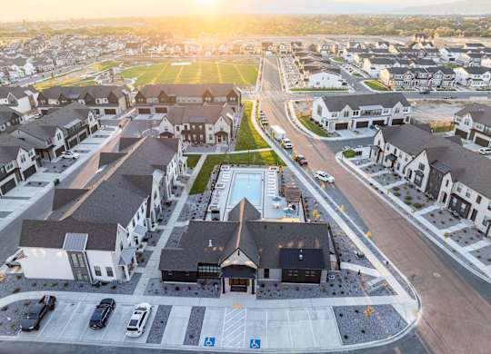 A sunset view of a residential area with houses and a swimming pool.