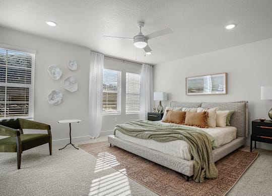 A bedroom with a bed, a chair, and a ceiling fan.